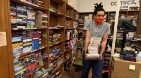 A man carries books in a bookstore. (Tony Dejak/AP)