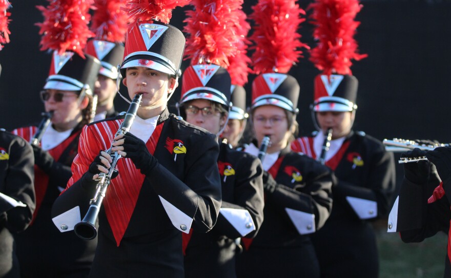 Fans and marching band members greet ISU football players and coaches