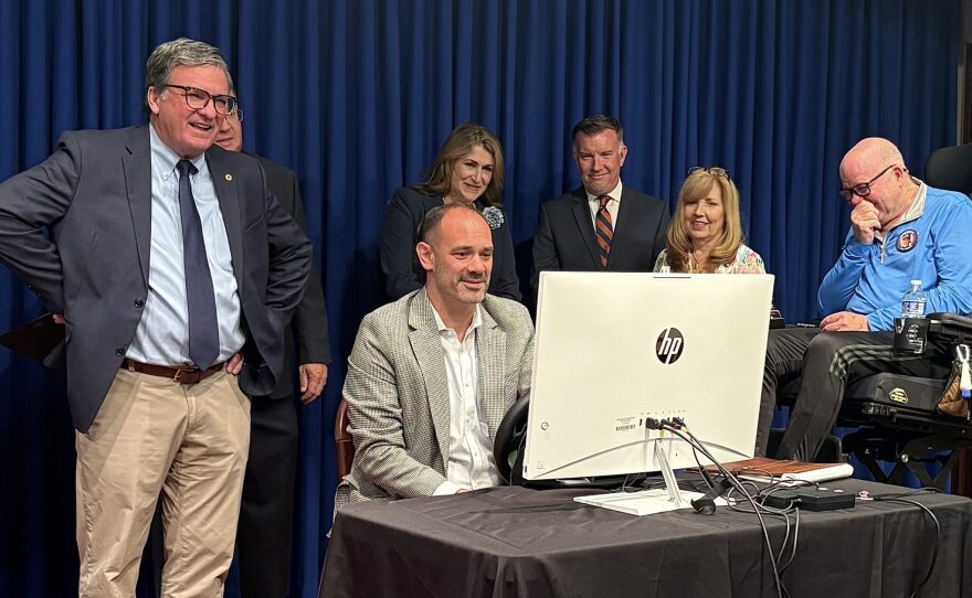 PennDOT Secretary Mike Carroll and Eileen and Paul Miller, whose son Paul Miller Jr. was killed by a distracted driver, watch as Insurance Commissioner Michael Humphreys uses a driving simulator Tuesday, May 27, 2025.
