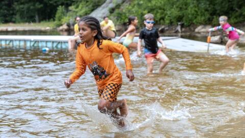 Campers run through the shallow water in the swimming area at Hale Education's day camp in Westwood. (Robin Lubbock/WBUR)