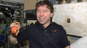 NASA astronaut Michael Barratt with floating tomato in Zvezda service module of the International Space Station.
