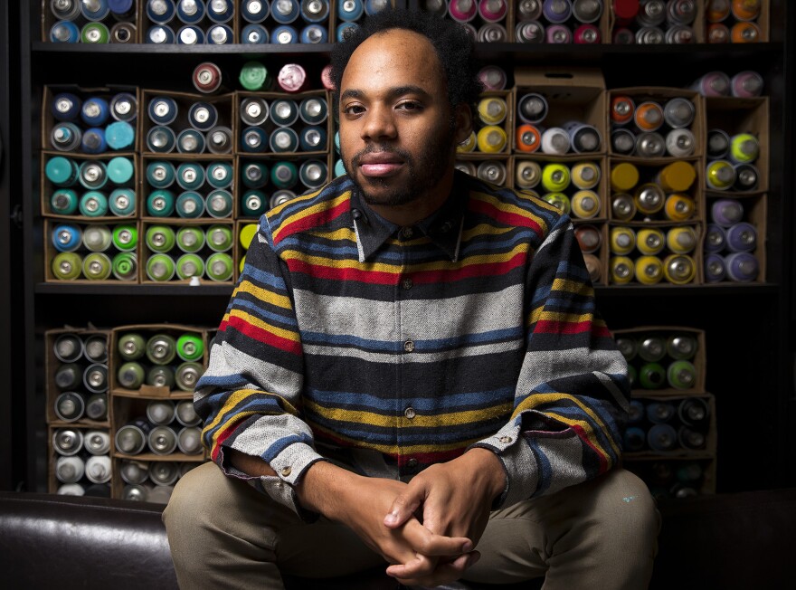 Christopher Paul Jordan poses for a portrait in front of a wall of spray paint cans on Wednesday, January 17, 2018, at his studio in Tacoma. 