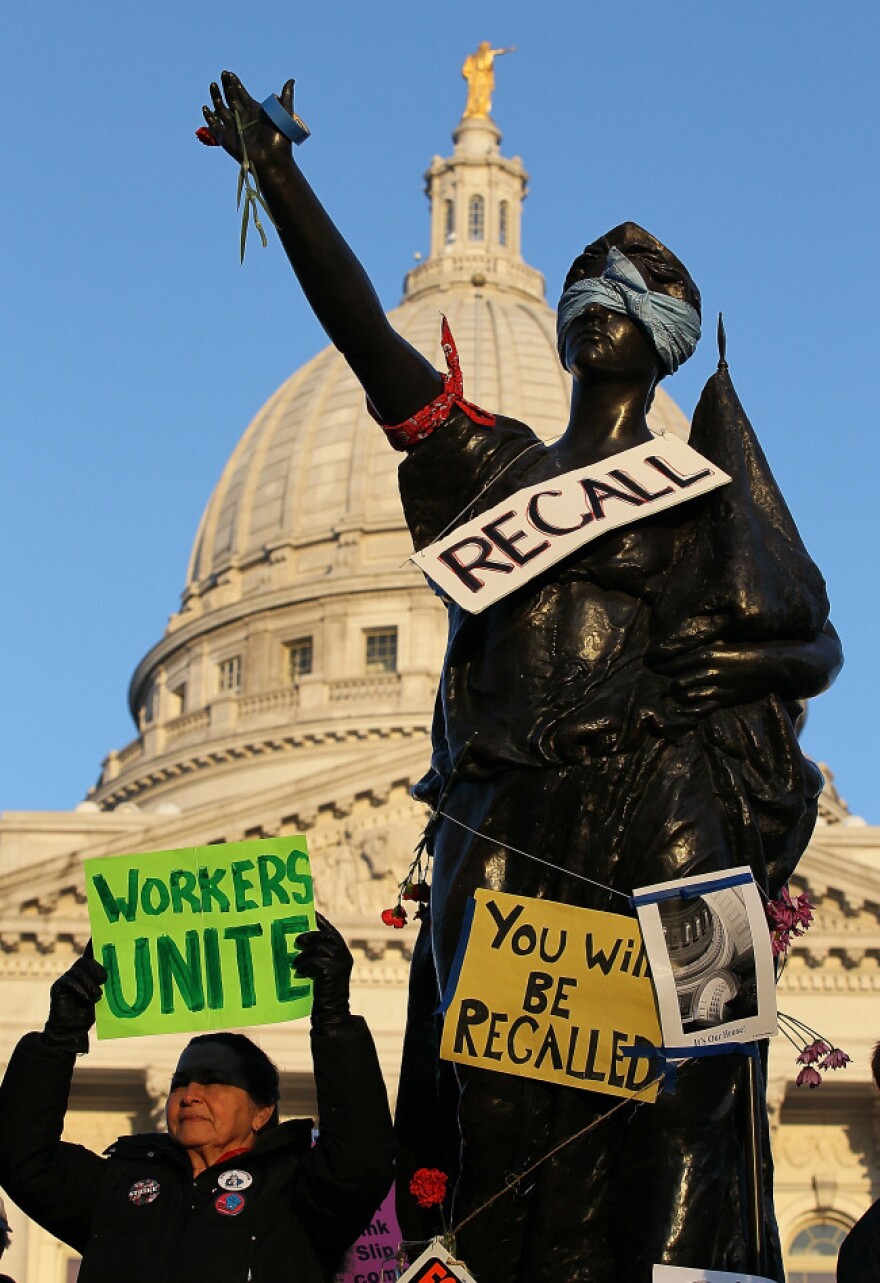 A sign to recall Wisconsin Gov. Scott Walker hangs on a statue in front of the Wisconsin State Capitol in Madison last March. The recall petition drive began in November, and Democrats will turn in signatures Tuesday.