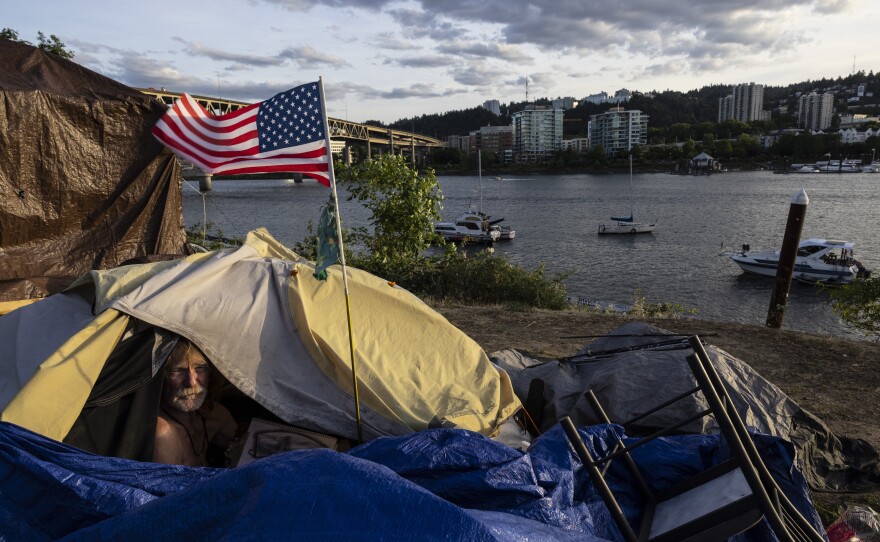 Frank, a homeless man sits in his tent with a river view in Portland, Ore., on Saturday, June 5, 2021.