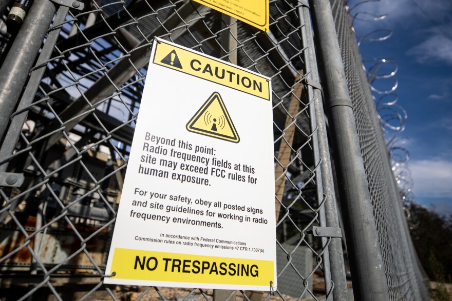 A yellow sign on a chain-link fence says radio frequency signals could harm humans