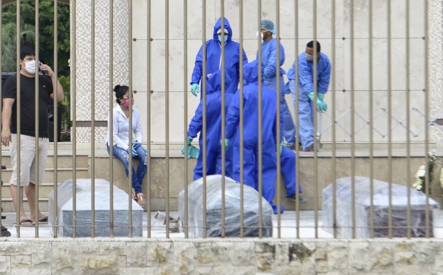 Cemetery workers in Guayaquil, Ecuador, deal with mounting coffins of COVID victims in April 2020.