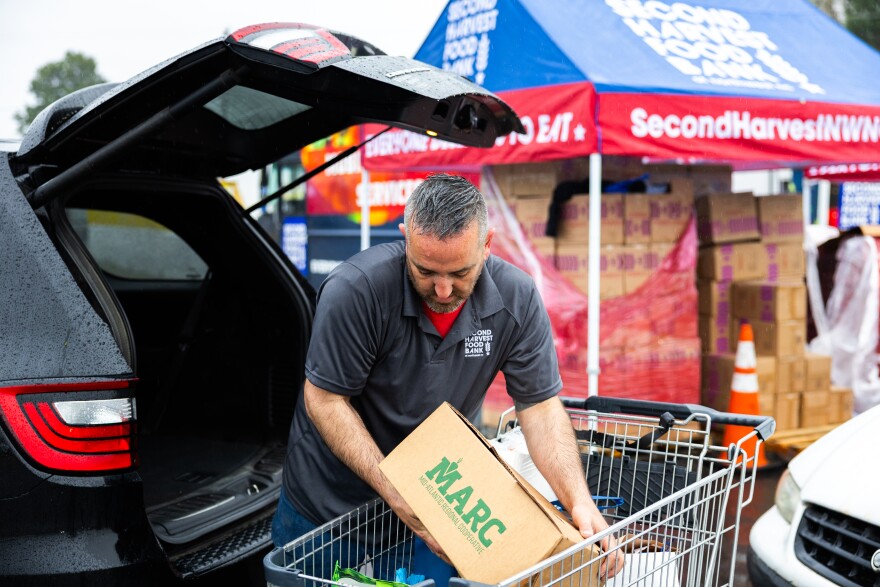 Daniel Weber, a truck driver at Second Harvest Food Bank of Northwest North Carolina, loads a box of produce into a vehicle during a food distribution. Photograph courtesy of Second Harvest Food Bank of Northwest North Carolina