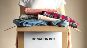 person holds a box with clothing donations