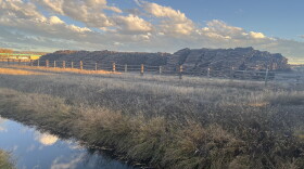A large pile of railroad ties stacked next to a small creek.
