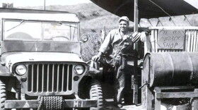 A man posing with an SUV at a motorcycle shop