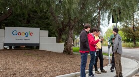 Technology workers stand in a group near signage for Google Inc at the Googleplex, the Silicon Valley headquarters of search engine and technology company Google Inc, Mountain View, California, April 7, 2017. (Smith Collection/Gado/Getty Images).