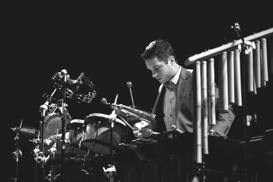 black-and-white photo of Cameron Leach playing percussion instruments