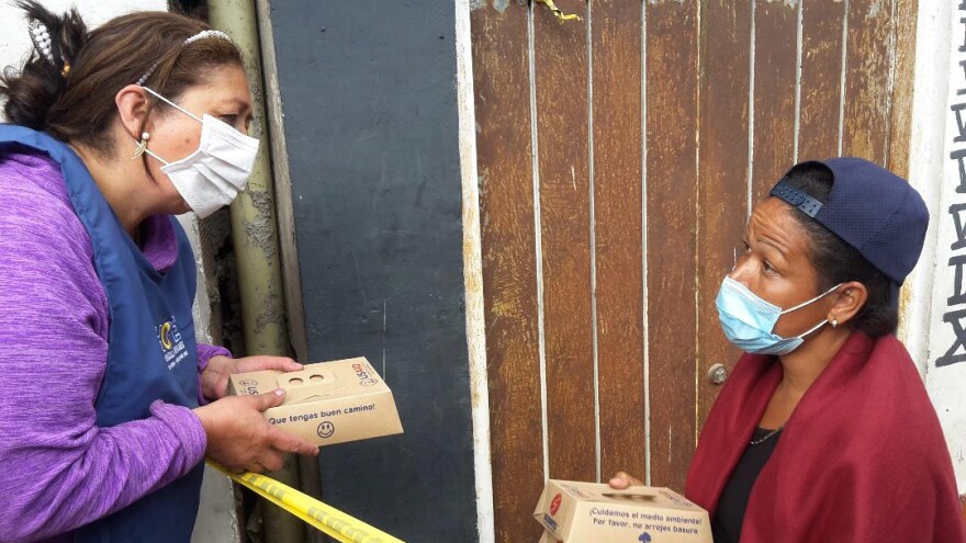 Marta Duque hands out food to a migrant from Venezuela.