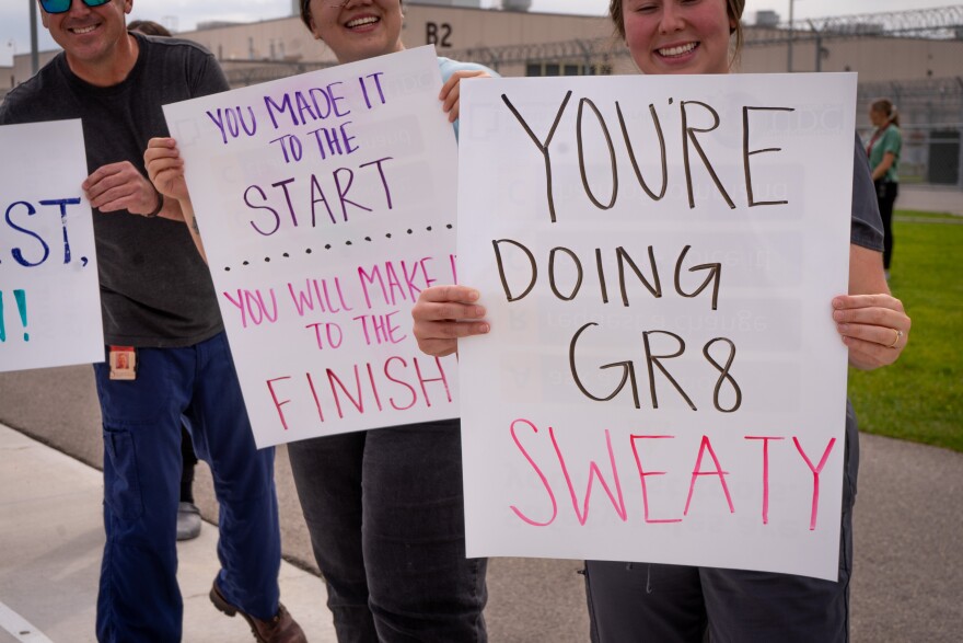 Health care staff from the Utah State Correctional Facility pose with handmade signs to encourage the runners.