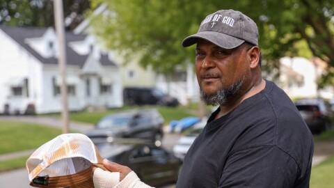 Hipolito Mateo stands in the front yard of his Rochester home Monday, May 18, 2026, holding the hat he said was marked with orange spray residue after ICE agents pepper-sprayed him during an encounter on Northland Avenue. Mateo said he was tased by the agents and fractured his wrist in a fall after agents blocked in his and his workers’ vehicles while they were preparing to begin the workday.