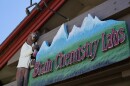  A close-up of a sign above a business, with the words “Brain Chemistry Labs” against a silhouette of the Tetons. There’s a brown bear on the sign wearing a lab coat and holding a beaker.