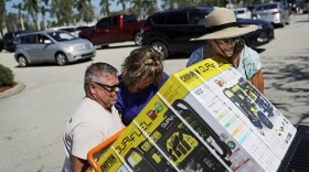 Don Jordan, from left, Lisa Jordan and Pat Lamke struggle to load a generator they just bought at a Costco store as it opened for the first time since Hurricane Irma passed through in Miromar Lakes, Fla., Wednesday, Sept. 13, 2017. (AP Photo/David Goldman)