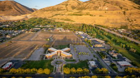 Aerial view of part of Brigham City. There's a chunk of land in the center that's undeveloped, with mountains rising in the near background.