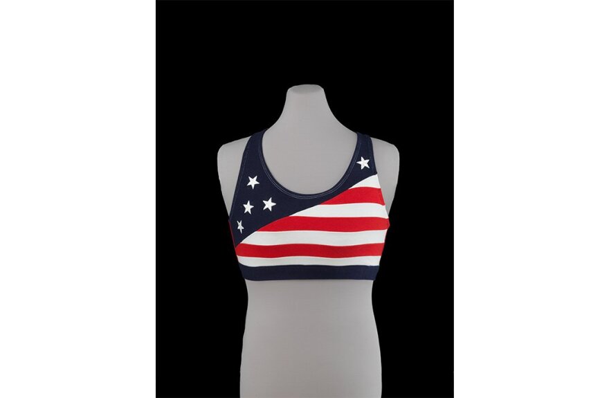 A gray mannequin torso wearing a sports bra decorated with the stars and stripes of the American flag.