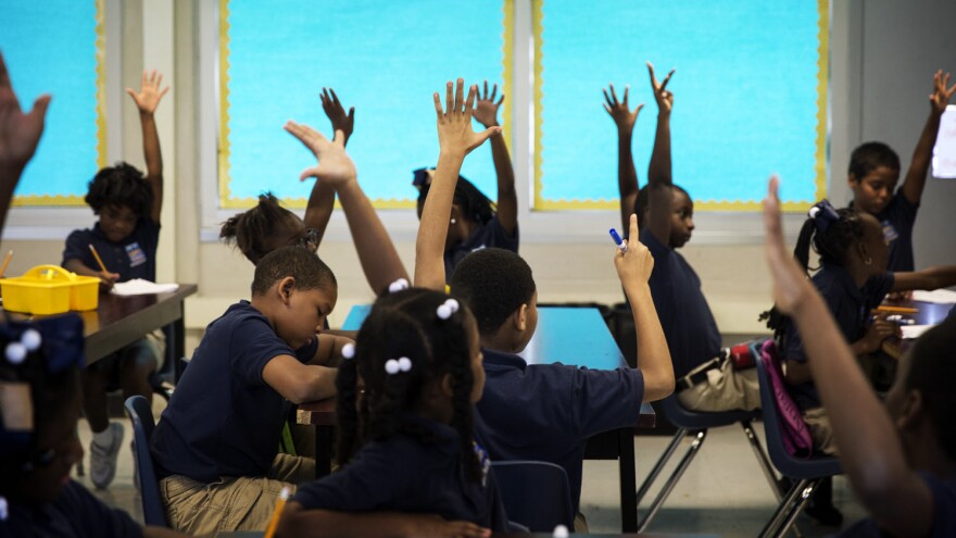 Students at KIPP Central City Primary School raise their hands during a social studies class on August 14, 2014 in New Orleans. The school's student body is nearly 100 percent black in a system that is 85 percent black.