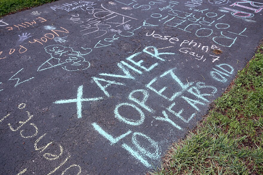 Colorful chalk displays the names and ages of the Uvalde, Texas school shooting. The most prominent one is "Xavier Lopez 10 years old"