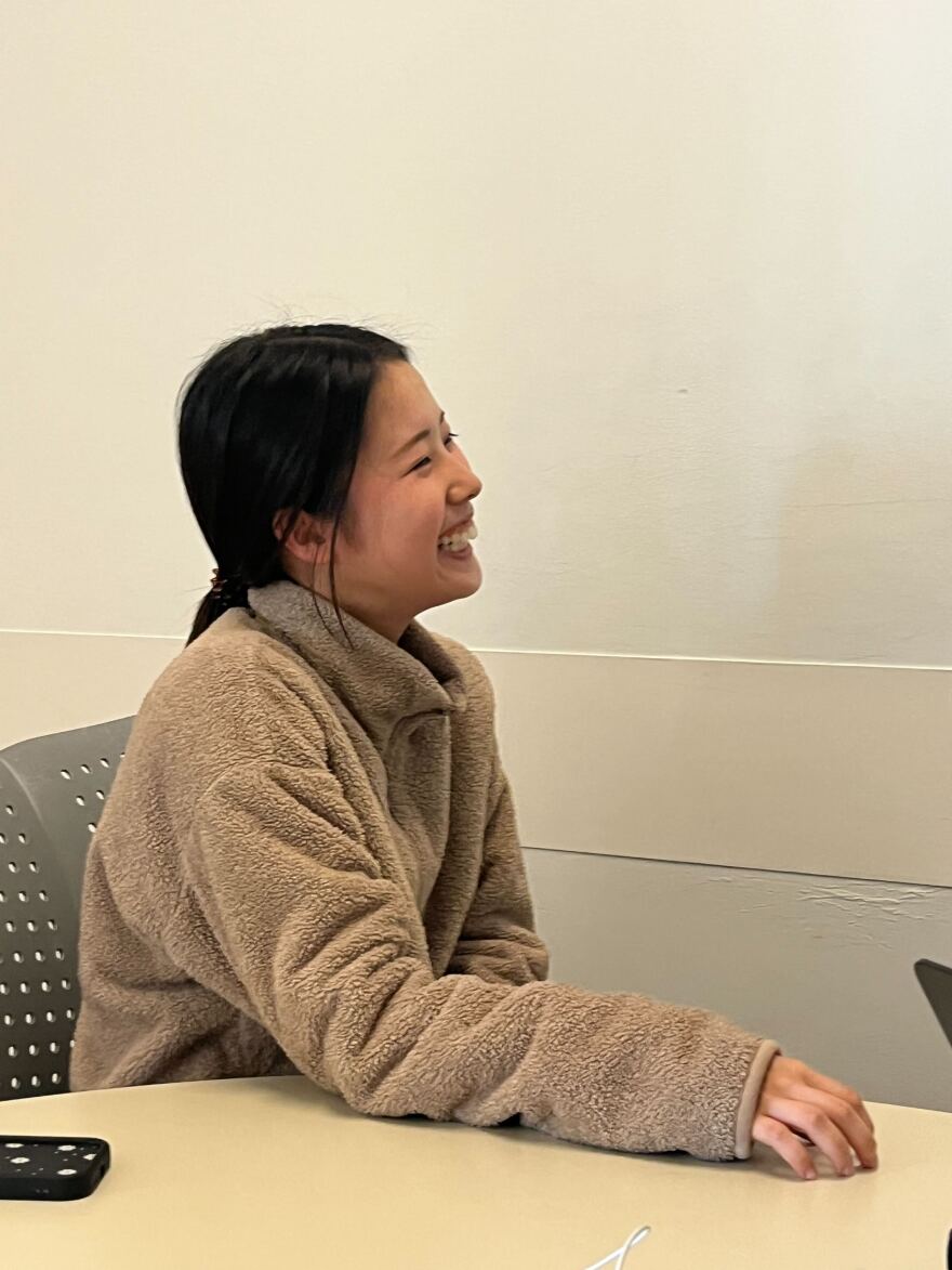 A woman wearing a fleece pullover and looking to the right is laughing.