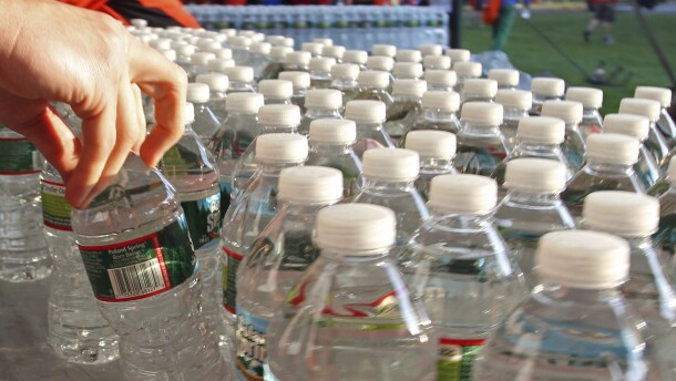 A hand reaches for one in a collection of plastic water bottles.