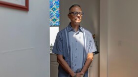 A man stands in the entryway to his kitchen at home.
