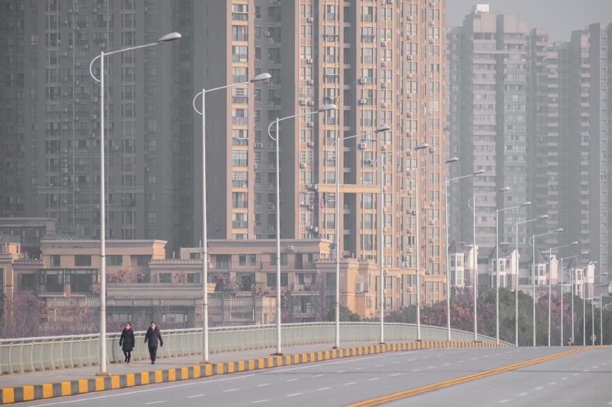 People walk down a deserted street in Wuhan, epicenter of the coronavirus outbreak, on Tuesday. Wuhan has gradually shut down all transportation channels for entering and leaving the city — no flights, trains, buses or boats.