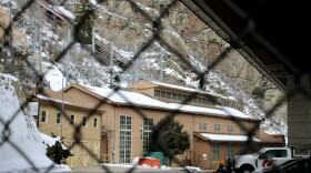 A beige building is visible through a chain link fence.