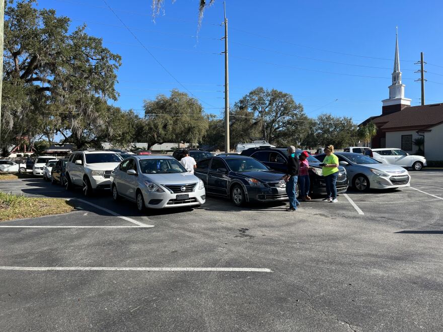 People wait in line to pick up food. Some got to the church at 4 this morning.