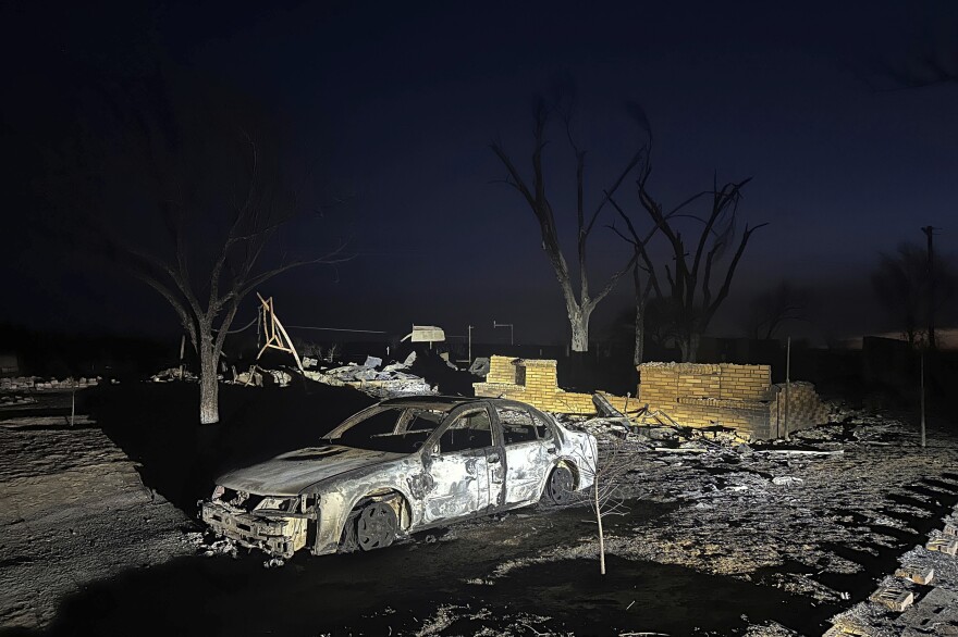 A charred vehicle sits near the ruins of a home after the property was burned by the Smokehouse Creek Fire.