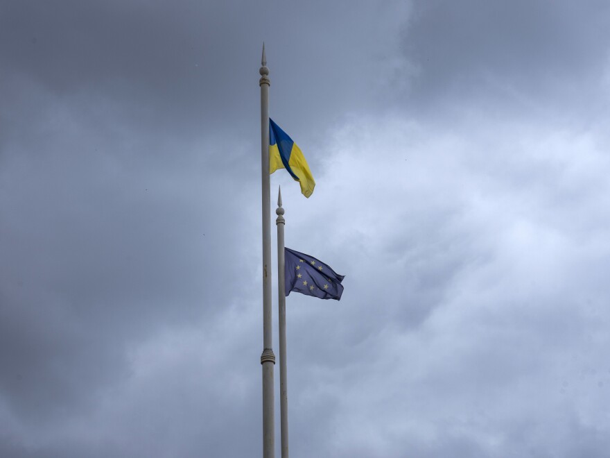 The Ukrainian (top) and European Union flags fly on poles in Kyiv on Thursday ahead of an EU summit in Brussels considering Ukraine's candidate status to join the 27-nation bloc.