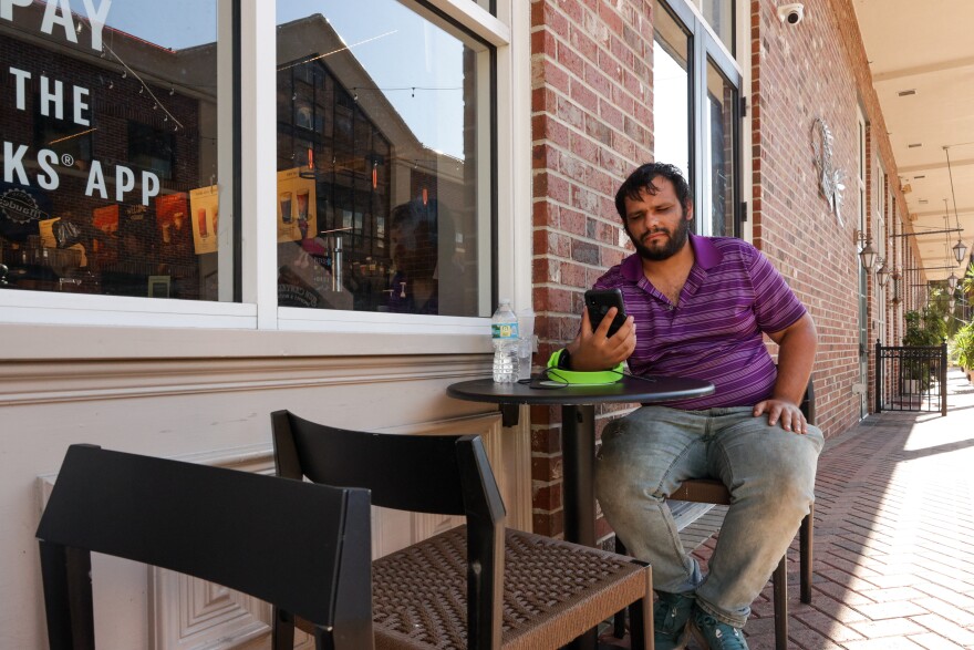 Brandon Jimenez, 25, sits at the Starbucks at Bo Diddley Plaza. He takes a phone call from a friend and will spend his day at Starbucks where the workers provide him with snacks and water. (Gabriel Velasquez-Neira/WUFT)