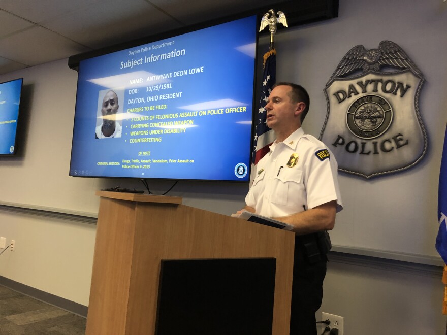 Dayton Police Interim Chief Matt Carper speaks at a podium in front of a monitor showing Antwyane Deon Lowe's information at a press briefing Wednesday afternoon. Last night, DPD officer Thadeau Holloway and Lowe were shot in an exchange of gunfire after responding to a counterfeit bill at a Dollar General Store. 