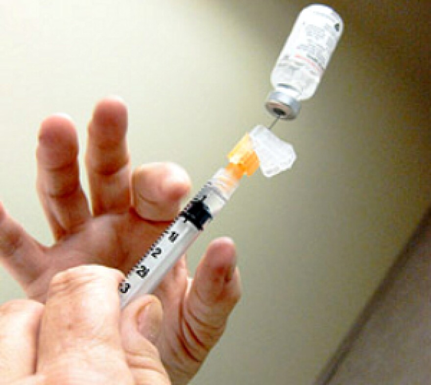 A flu vaccine gets placed inside a needle.