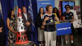 Boston Mayor Michelle Wu and a host of Massachusetts and Scottish officials look on as Massachusetts Gov. Maura Healey lauds a traffic cone at Logan Airport (Robin Lubbock/WBUR)