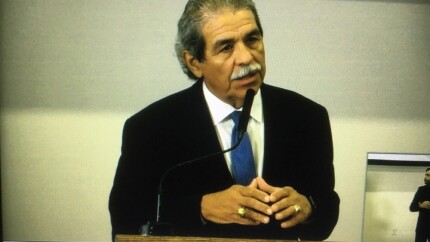 photo of a man, Dallas superintendent Michael Hinojosa, standing at a lectern speaking into a microphone