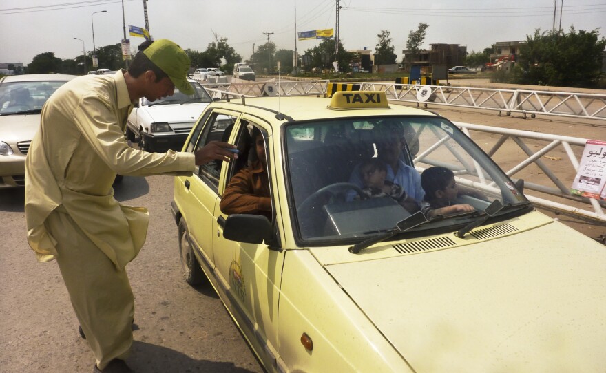 Khan Wali, 21, scrutinizes passing cars for young children at the traffic checkpoint. If a child appears to be younger than 5, the driver must pull over.