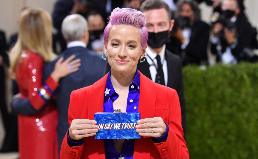 U.S. soccer player Megan Rapinoe holds up her bag at the entrance to the Met Gala.