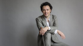 Photo of conductor Eric Jacobsen holding a conducting baton. 
