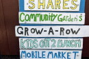 Colorful sign listing program offerings of a food program including "shares" "grow-a-row" and "composting"