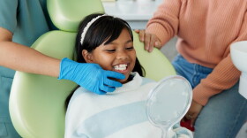 Child, dentist or examination of teeth in surgery, trust or patient by doctor for oral hygiene. Girl, parent or support in consultation by tooth professional or mirror for interactive dental checkup.