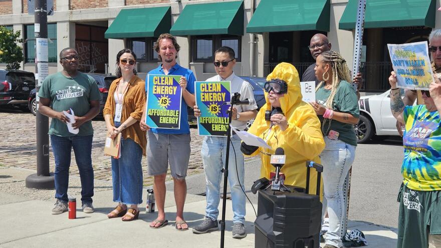 PUSH Buffalo member Luz Velez, in yellow, stands in a full-body personal protection suit, talking about her concerns with the use of nuclear power.