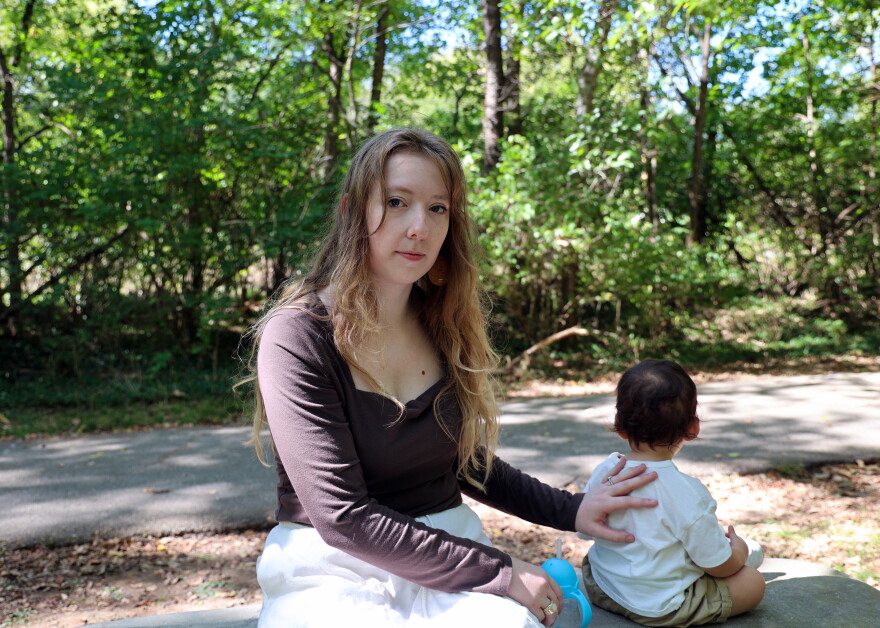 Madie Perez, 22, rests a hand on her 14-month-old son’s back as he sits beside her on a stone bench at Sequiota Park in Springfield, Missouri, on Wednesday, Oct. 7, 2026. Perez, a former childcare worker, is raising her son solo now. She hopes to write children’s books that explain hard topics to young children one day.