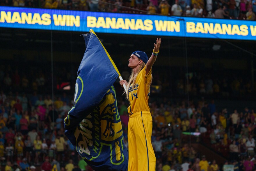 Dakota Albritton waves the Savannah Banana flag while standing on stilts after the Bananas beat the Party Animals at Busch Stadium on Friday, July 18, 2025, in downtown St. Louis.