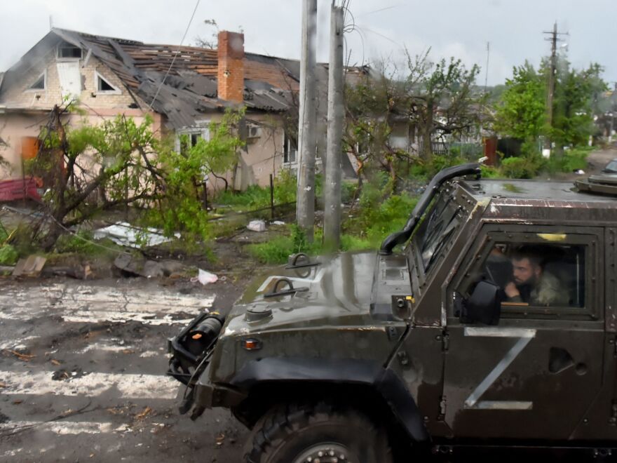 A Russian military vehicle painted with the letter Z drives past destroyed houses in the Ukrainian city of Mariupol on Wednesday.