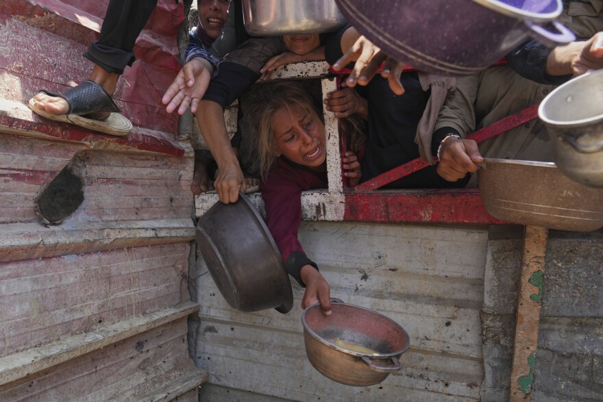 Palestinians struggle to get donated food at a community kitchen, in Gaza City, northern Gaza Strip, Saturday, July 26, 2025. (AP Photo/Abdel Kareem Hana)
