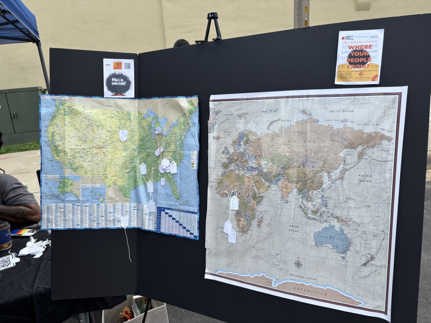 Two maps, one of the US and one of the world, are pinned to a black fold-out board. There are tags pinned to various spots on the maps.