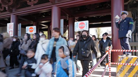 A police officer controls visitors to walk slowly as they move to the main hall to pray for good luck during their "hatsumode," or first visit of the year to a shrine or temple, at Kawasaki Daishi temple Saturday, Jan. 3, 2026, in Kawasaki near Tokyo.